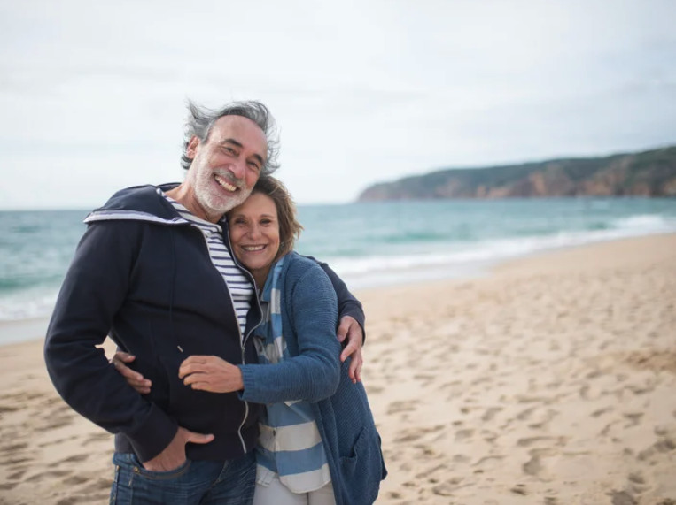 A happy middle-aged couple in the moment enjoying their walk on the beach | Primal Reset