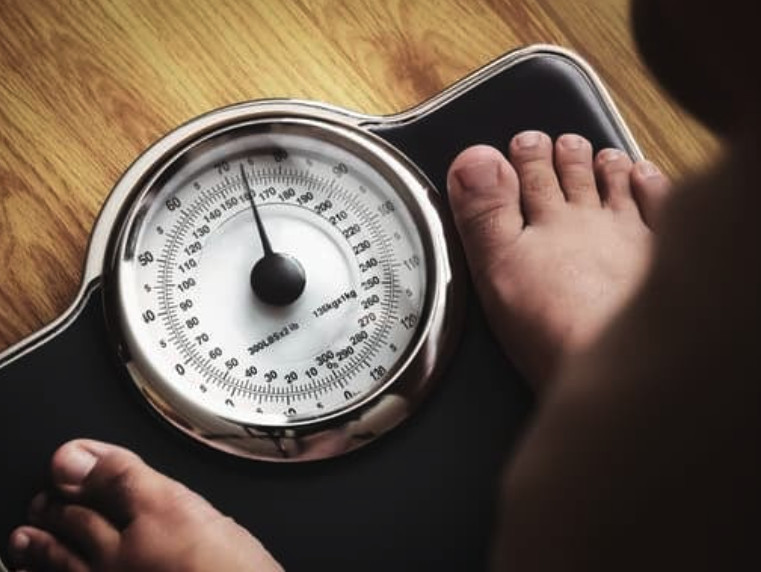 Older man standing on scales showing an unhealthy weight | Primal Reset
